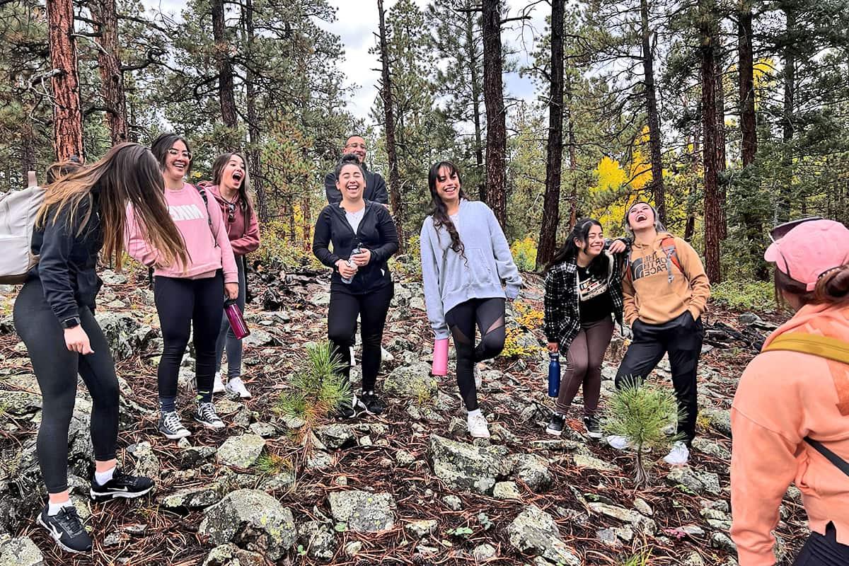 Estudiantes embajadores riendo y divirtiéndose mientras realizan una caminata por la naturaleza durante un ejercicio de desarrollo.